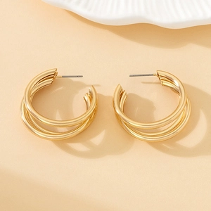 Detailed close-up of triple-layered golden hoop earrings with a high-shine metallic finish