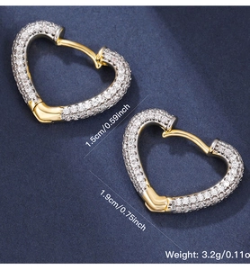 Detail of gold heart-shaped hoop earrings with clear zircon stones on a blue background