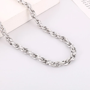 Macro detail of high-polish silver stainless steel twist chain necklace on a white surface