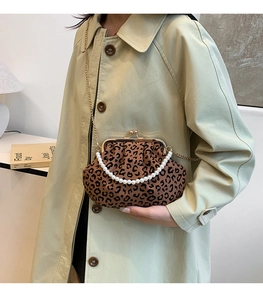 Detail of leopard print pleated bag with pearl handle and gold chain strap on model