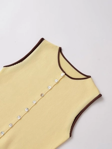 Détail d'un top sans manches en maille jaune avec liseré marron et boutons nacrés