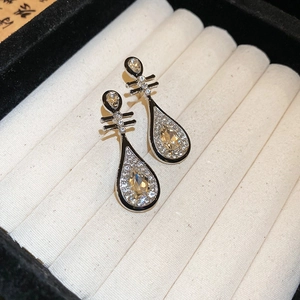 Detail von silbernen Tropfenohrringen mit gelbem Zirkon und Kristallen in einer Box