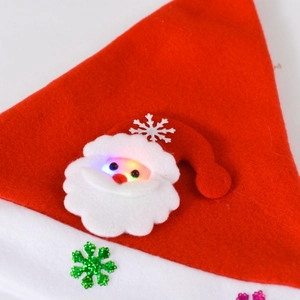 Close-up of a red festive Santa hat with glowing Santa Claus motif and sequin snowflakes