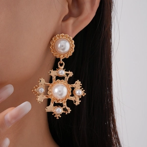 Vintage golden cross earrings with white pearls in a retro baroque style on a model