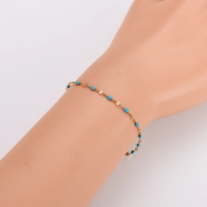 Minimalist bohemian gold chain bracelet with turquoise beads on model's wrist