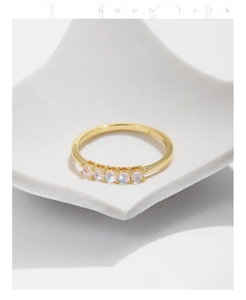 Macro shot of minimalist gold five-stone opal ring on a white matte display tray