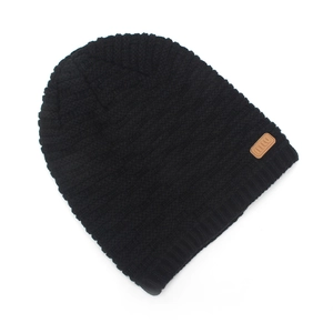 Detail of black knit beanie texture with premium brown leather patch and miu logo
