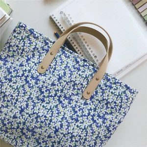 Detail view of Klein blue floral tote with leather handles and gold rivet reinforcement