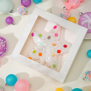 Sparkly white star Christmas ornament with colorful sequins in a windowed gift box
