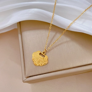 Detailed macro of gold titanium steel ruyi lock pendant with engraved fu character