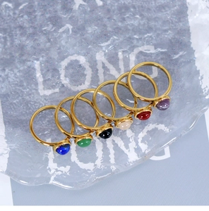 Detailed view of six gold titanium rings with colorful round natural stone cabochons