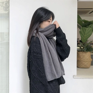 Detail showing soft dark grey knitted scarf texture and weaving pattern on model
