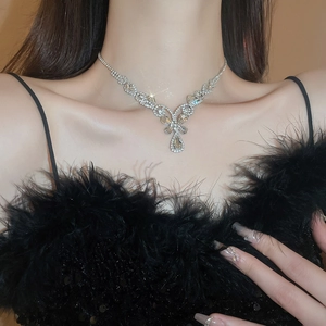 Close-up of sparkling floral and teardrop pendant necklace worn by a model