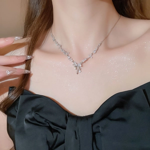 Close-up of a sparkling zircon bow pendant necklace with tassels on a female model