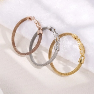 Three mesh chain bracelets in gold, silver, and rose gold finishes on soft white faux fur
