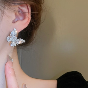 Side view of shimmering zircon butterfly earrings worn by a model in close-up detail