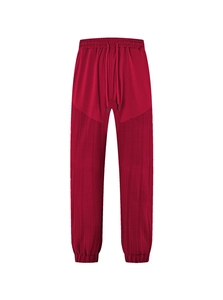 Detail of red drawstring sweatpants with textured patchwork design and elastic cuffs