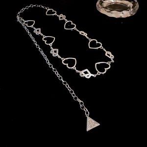 Detailed view of hollow heart links and triangle pendant on a silver metal waist chain