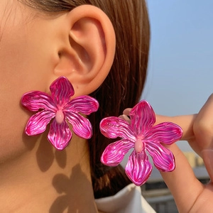 Détail macro de boucles d'oreilles orchidées rouge rose avec texture et finition métallique