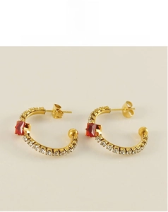 Detailed close-up of 18K gold-plated C-shaped earrings with red zircon and crystal accents