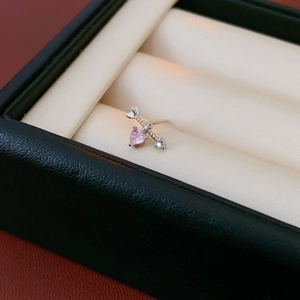 Macro shot of silver cupid arrow earring with pink heart gemstone and sparkling zircons