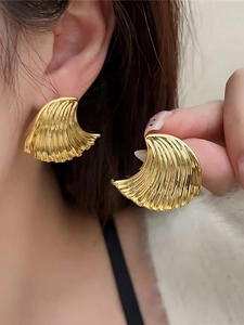 Macro detail of golden wave textured earrings with irregular minimalist shell pattern