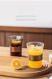Close-up of ribbed glass cup with walnut wood thermal sleeve on a wooden tray