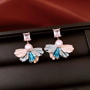 Détail macro de la boucle d'oreille vintage avec zircon, perle blanche et pétales en émail bleu