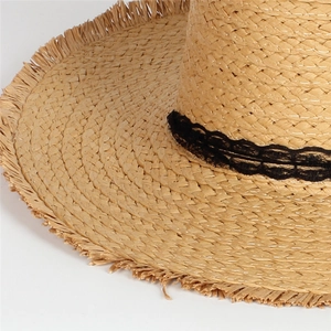 Detailed shot of straw sun hat with black lace trim and frayed fringe edge texture