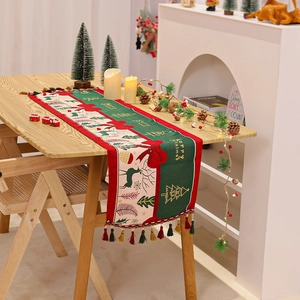 Detailed view of Christmas table runner with reindeer patterns and colorful tassel edges