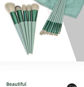 Close-up of 13 professional makeup brushes with green gradient handles and cleaning cloth