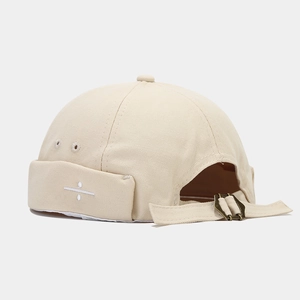 Detail view of beige cotton docker hat featuring adjustable strap and metal buckle closure