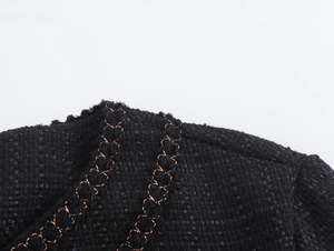 Dettaglio dell'abito in tweed nero con ricamo a catena dorata e tessuto a trama