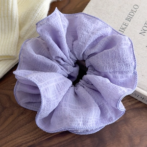 Detailed texture of oversized lavender pleated chiffon scrunchie on wooden background