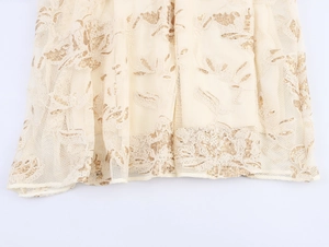 Detailed view of beige mesh fabric with golden floral embroidery and sequin embellishments