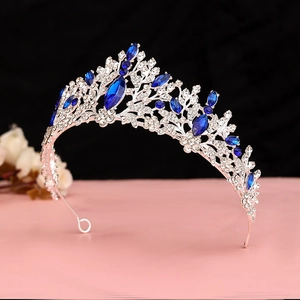 Detailed view of silver crown with deep blue gems and sparkling white rhinestones