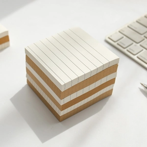 Vierkante memoblok-set met wit gelinieerd en bruin blanco papier op een wit bureau