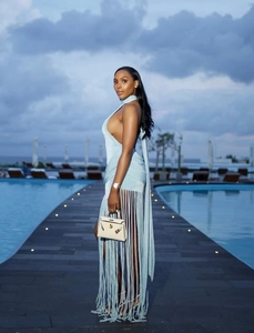 Detailed backless halter dress with long side tassels and light blue fabric in a luxury pool setting