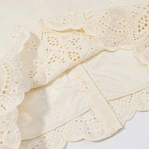 Close-up of cream lace embroidery details with double-layer fabric and scallop edge finish