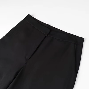 Detailed close-up of the black trousers waistline with button fly and side pocket design