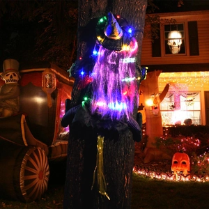 Detail of Halloween crashing witch with glowing purple hair and LED lights on a tree
