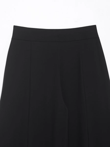 Close-up of waistband stitching and pleat details on black high-quality woven trousers