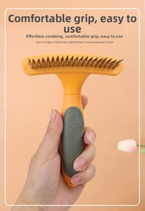 Detail view of double-row pet rake comb with ergonomic orange handle and metal teeth