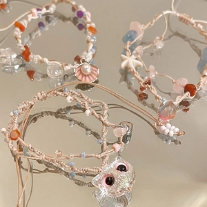 Detailed view of woven bracelets with pink cat, shell, and white starfish charms