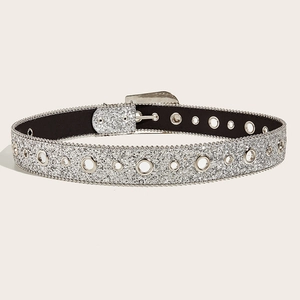 Detailed view of silver sequin belt with metal buckle and grommets on beige backdrop