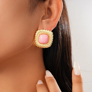 Close-up of a model wearing square gold earrings set with soft pink gemstones