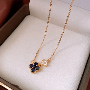 Détail macro du pendentif trèfle plaqué or 18 carats avec pierres bleues et zircone