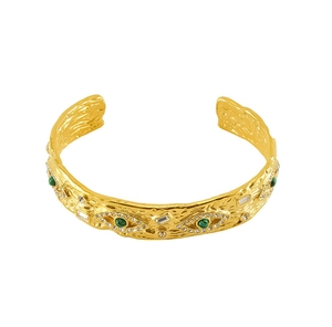 Detailed view of gold malachite cuff bracelet with vintage hammered texture and evil eyes