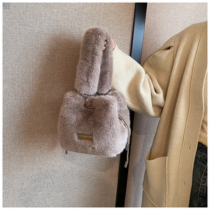 Detail of plush bucket bag featuring metal drawstring and gold love every day plaque