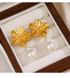 Macro shot of gold flower earrings with baroque pearls on a velvet jewelry box padding